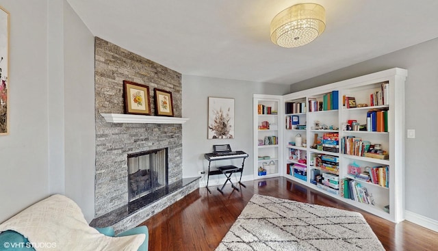 sitting room with dark hardwood / wood-style flooring and a stone fireplace