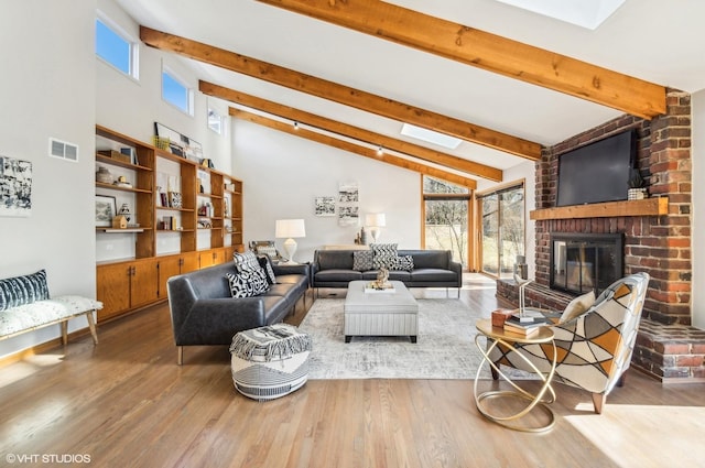 living room with a fireplace, a skylight, hardwood / wood-style floors, and beam ceiling