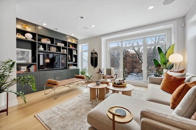 living area with built in features and light wood-type flooring