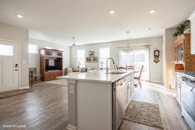 kitchen with a kitchen island with sink, a sink, a healthy amount of sunlight, light wood-style floors, and appliances with stainless steel finishes