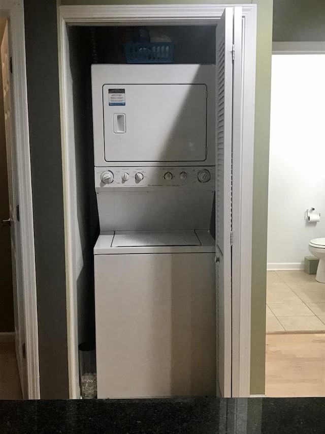 laundry area with stacked washer and dryer and tile patterned floors