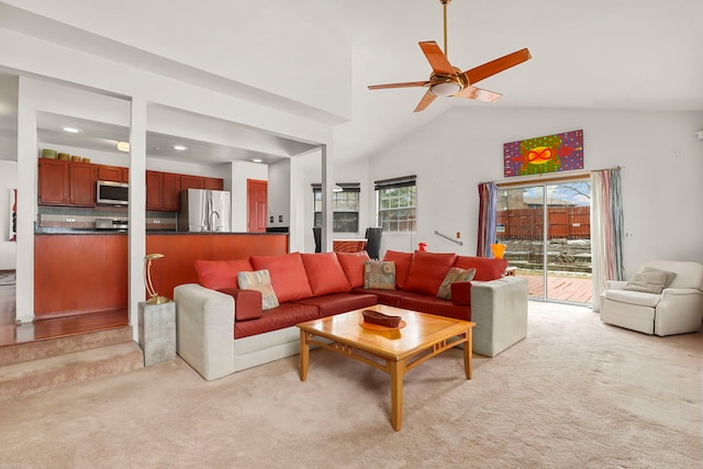 living room with high vaulted ceiling, a ceiling fan, and light colored carpet