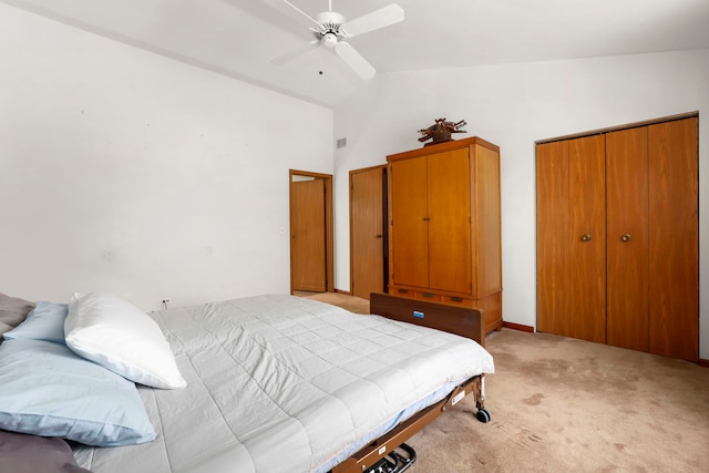 bedroom featuring lofted ceiling, light colored carpet, a ceiling fan, visible vents, and a closet