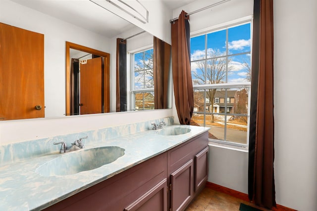 bathroom with double vanity, a sink, visible vents, and baseboards