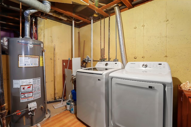 laundry room featuring water heater, laundry area, light wood-style floors, and washer and dryer