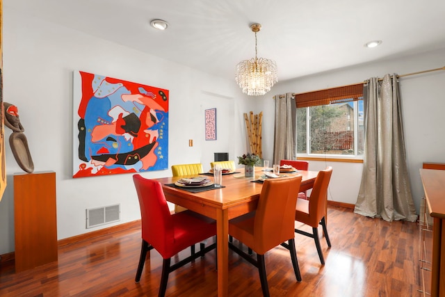 dining area featuring a notable chandelier, baseboards, visible vents, and wood finished floors