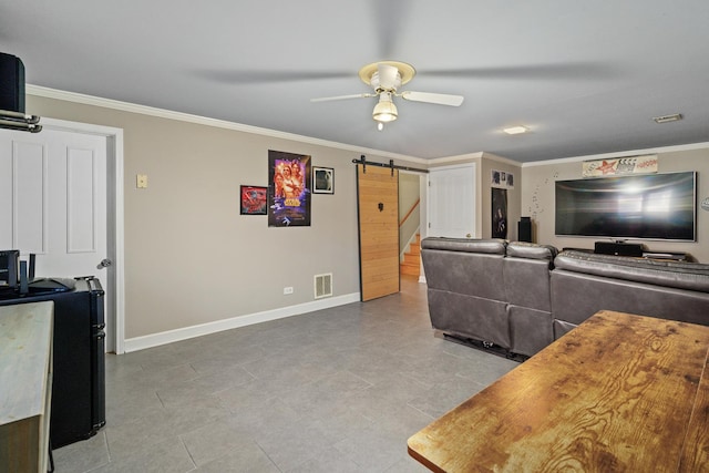 living area featuring a barn door, visible vents, baseboards, ceiling fan, and ornamental molding