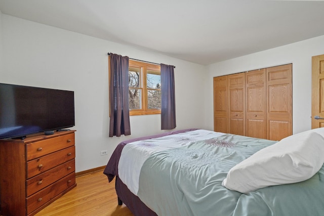 bedroom with light wood-style flooring, baseboards, and a closet