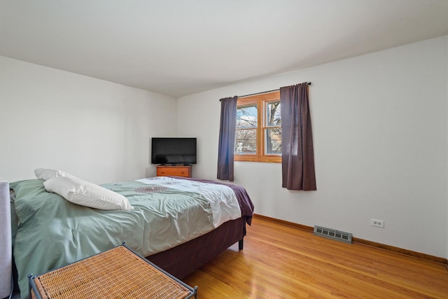 bedroom featuring visible vents, baseboards, and wood finished floors