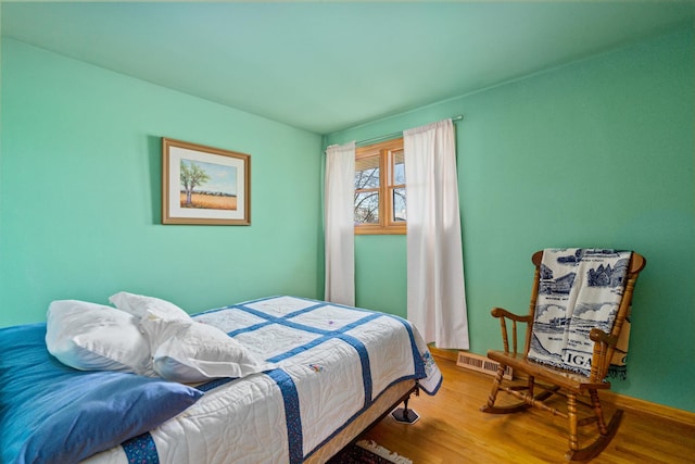 bedroom featuring baseboards, visible vents, and wood finished floors