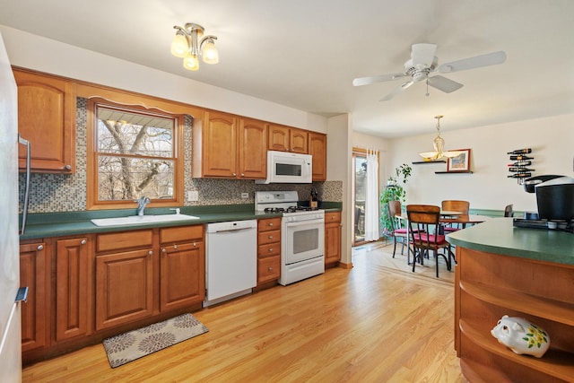 kitchen featuring white appliances, a wealth of natural light, a sink, and light wood finished floors