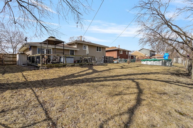 back of house featuring a lawn, fence, a deck, and a fenced in pool