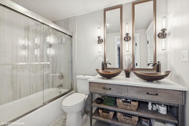 bathroom featuring combined bath / shower with glass door, vanity, and toilet