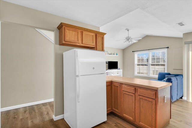 kitchen with lofted ceiling, light wood-type flooring, kitchen peninsula, and white refrigerator