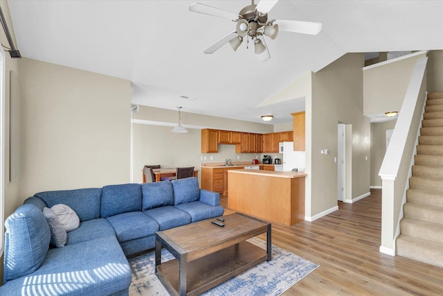 living room with sink, vaulted ceiling, ceiling fan, and light wood-type flooring