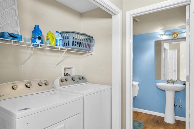 clothes washing area featuring hardwood / wood-style flooring, independent washer and dryer, and sink