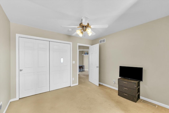 unfurnished bedroom featuring light colored carpet, ceiling fan, and a closet