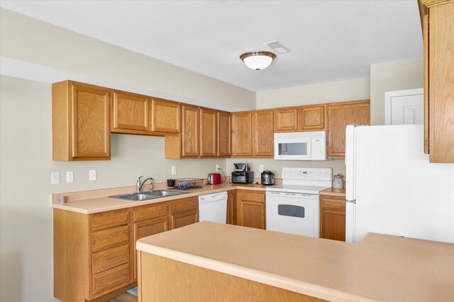 kitchen with sink, white appliances, and kitchen peninsula