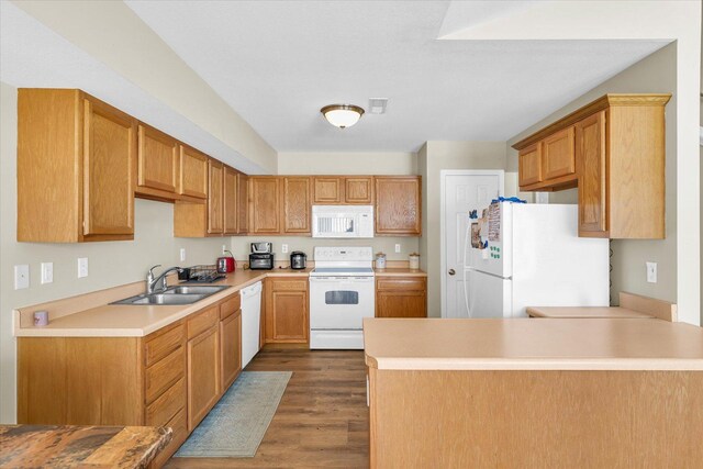 kitchen with white appliances, dark hardwood / wood-style floors, kitchen peninsula, and sink