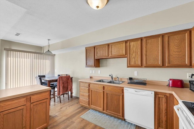 kitchen featuring sink, a textured ceiling, hanging light fixtures, light wood-type flooring, and white appliances