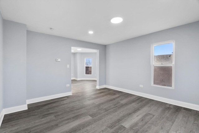 spare room featuring a healthy amount of sunlight and dark wood-type flooring