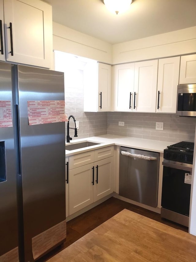 kitchen with appliances with stainless steel finishes, decorative backsplash, sink, and white cabinetry