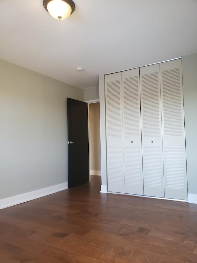 unfurnished bedroom featuring dark wood-type flooring and a closet