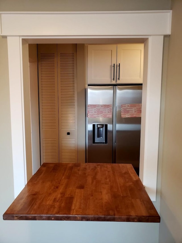 kitchen with stainless steel fridge and butcher block countertops