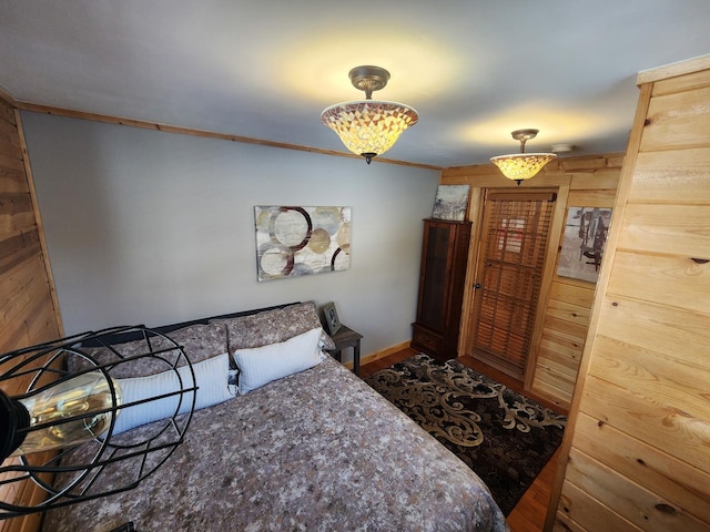 bedroom featuring ornamental molding, wooden walls, and baseboards