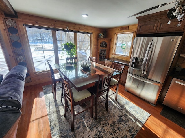 dining room featuring light wood-type flooring and wooden walls