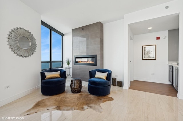 sitting room featuring expansive windows, a water view, a fireplace, and light hardwood / wood-style floors