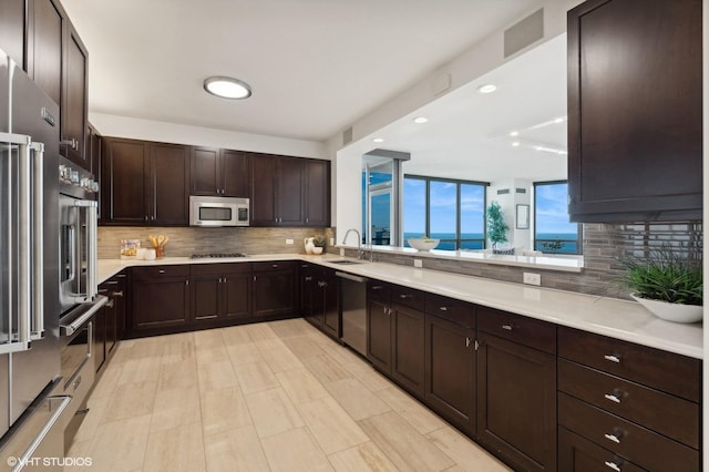 kitchen with sink, decorative backsplash, dark brown cabinets, and appliances with stainless steel finishes