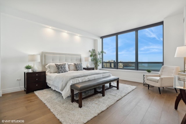 bedroom with a water view and light hardwood / wood-style floors