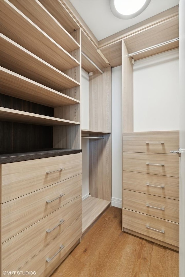 walk in closet with light hardwood / wood-style floors