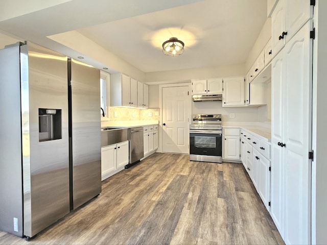 kitchen with white cabinetry, appliances with stainless steel finishes, and hardwood / wood-style flooring