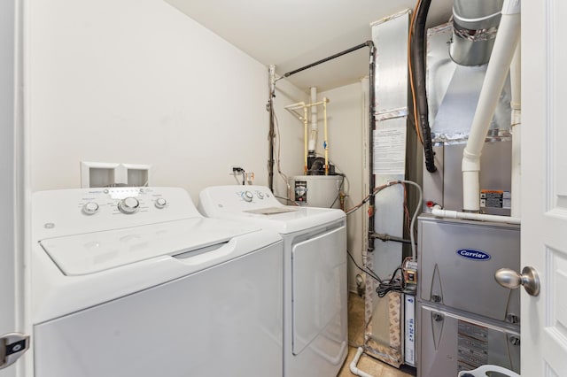 clothes washing area with water heater, laundry area, separate washer and dryer, and heating unit