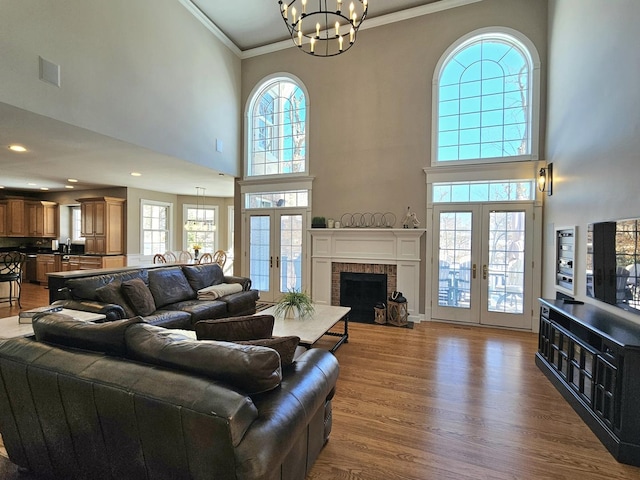 living room with french doors, an inviting chandelier, wood-type flooring, ornamental molding, and a wealth of natural light