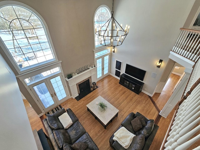 living room with an inviting chandelier, hardwood / wood-style floors, a towering ceiling, and french doors