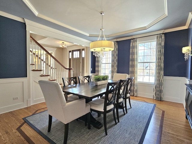 dining area with crown molding, a tray ceiling, a chandelier, and hardwood / wood-style floors