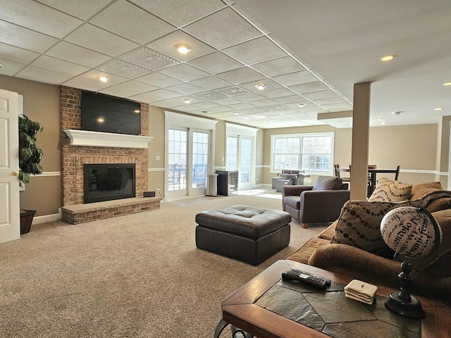 living room featuring a paneled ceiling, a fireplace, and carpet