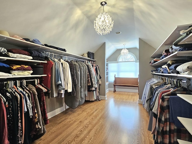 spacious closet with wood-type flooring, lofted ceiling, and a chandelier