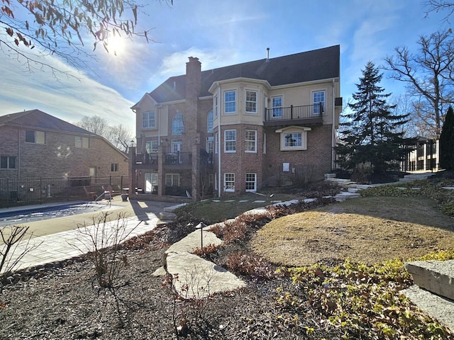 rear view of house featuring a balcony and a community pool