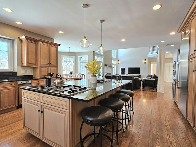 kitchen with pendant lighting, a kitchen bar, hardwood / wood-style flooring, a center island, and stainless steel gas cooktop