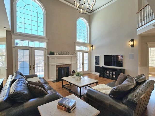 living room with hardwood / wood-style flooring, ornamental molding, a towering ceiling, and french doors