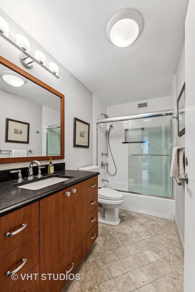 full bathroom with enclosed tub / shower combo, vanity, and toilet