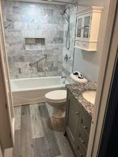 full bathroom with vanity, wood-type flooring, toilet, and tiled shower / bath