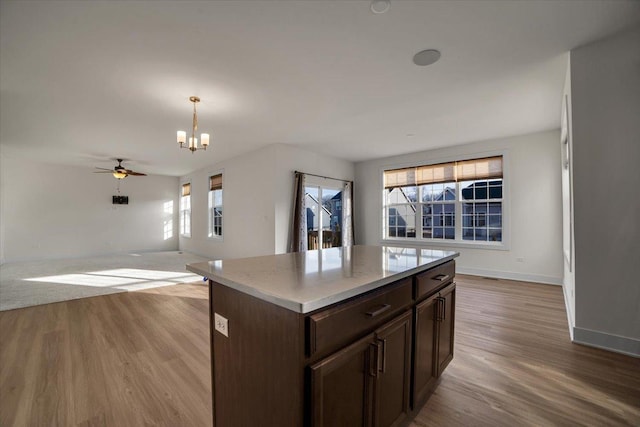 kitchen with a center island, decorative light fixtures, light hardwood / wood-style floors, a healthy amount of sunlight, and dark brown cabinetry