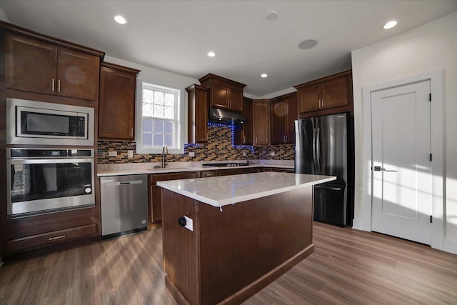 kitchen with appliances with stainless steel finishes, sink, a kitchen island, and hardwood / wood-style flooring