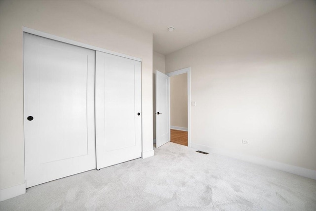 unfurnished bedroom with light carpet and a closet