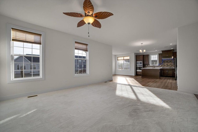 unfurnished living room with ceiling fan and dark colored carpet